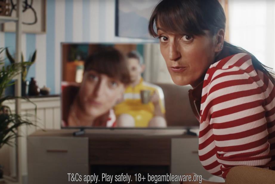 Comedian Jo Griffin in the new Tombola ad - she is looking at the camera in the foreground, while her image appears on a TV in the background